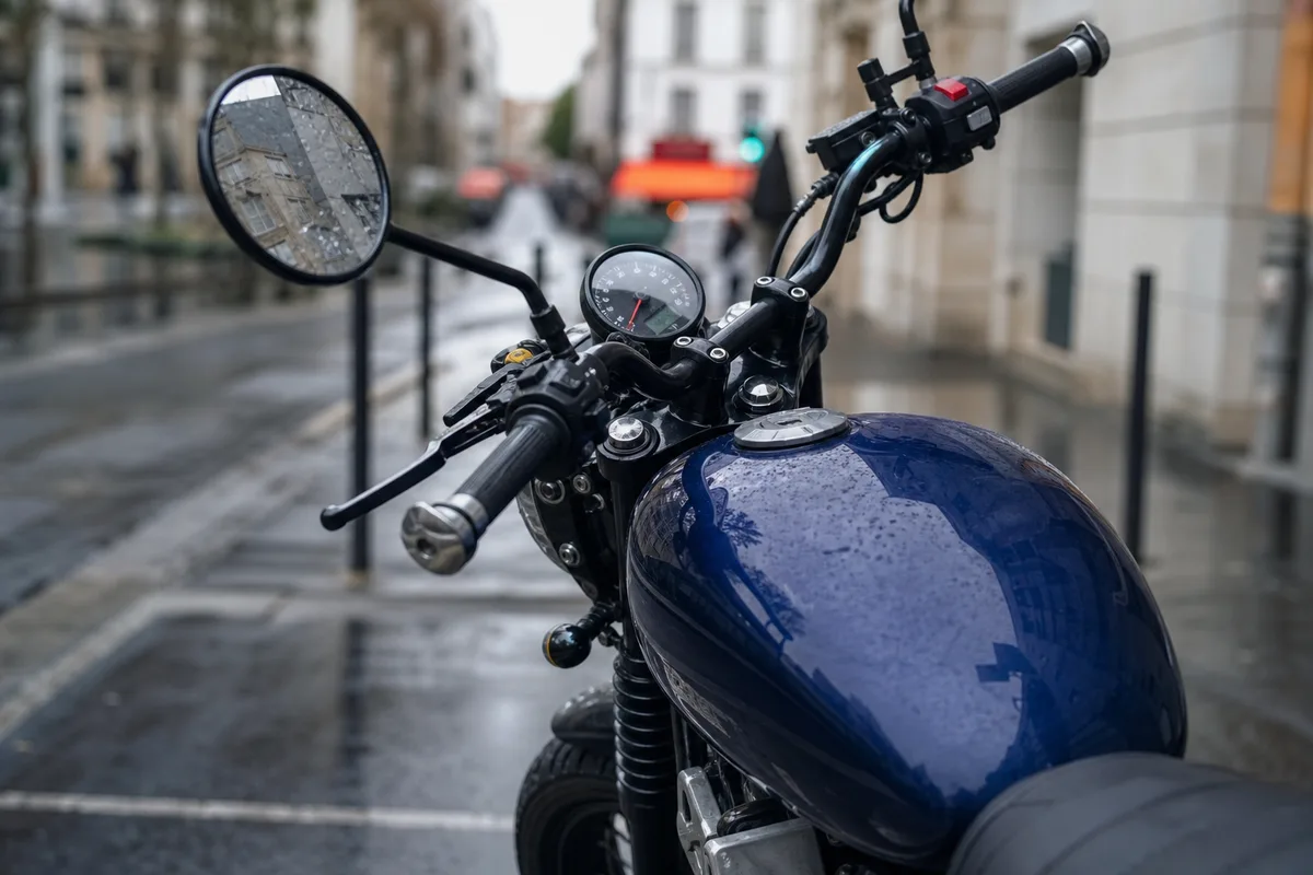 Moto stationnée sur une place de parking urbaine en France, guidon et rétroviseur au premier plan