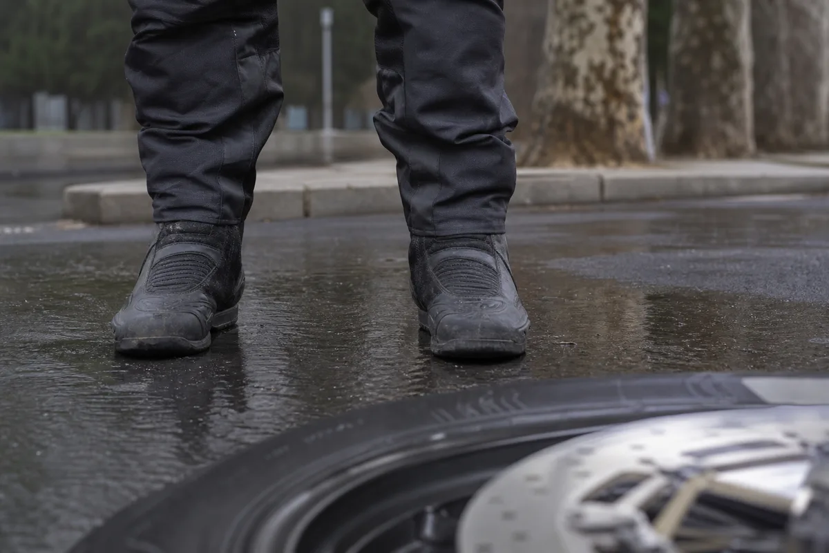 Motard en équipement complet vérifiant l’appui de ses pieds au sol sur une moto à l’arrêt