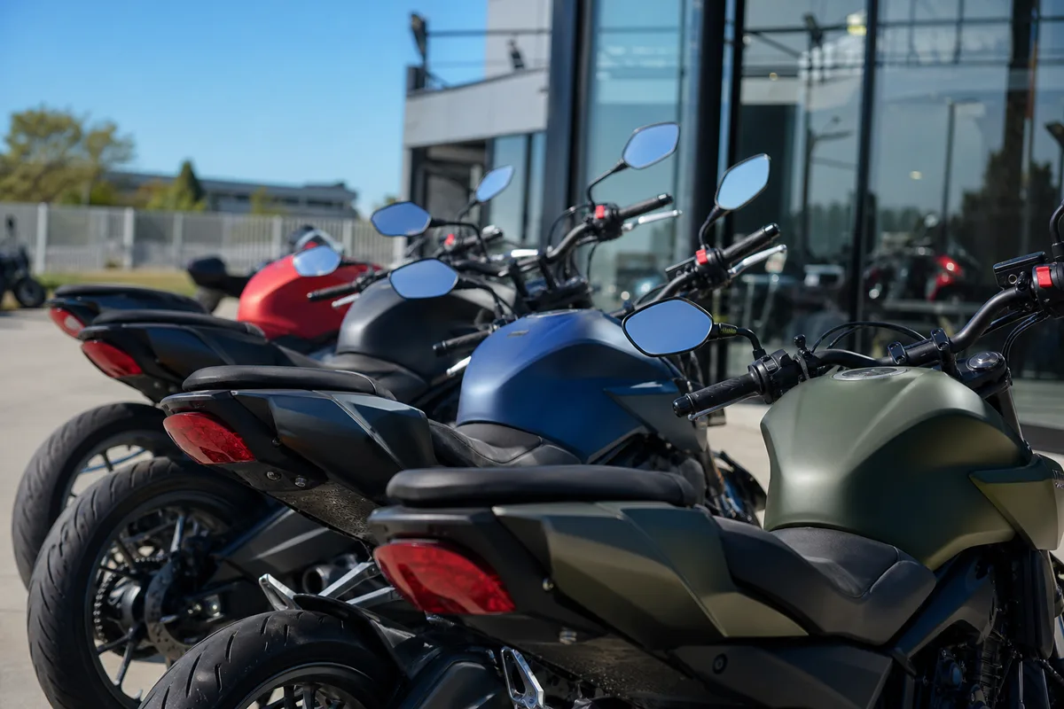 Alignement de roadsters et de trails devant une concession moto française par temps clair